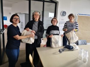 Die Kolleginnen halten lächelnd selbst gepackte Beutel in die Höhe.