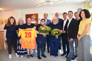Das Betreuer:innen Team der WG Eisenstadt und hochrangige Gäste aus der Verwaltung von Rettet das Kind Burgenland posieren lächelnd für ein Gruppenfoto.