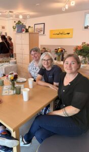 Zwei Betreuerinnen der Wohngemeinschaft sitzen gemeinsam an einem Holztisch und trinken Kaffee.